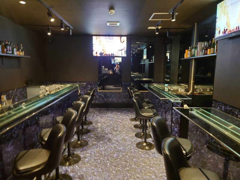 店内の全景。左右にガラスのカウンターと黒いチェアが並ぶ